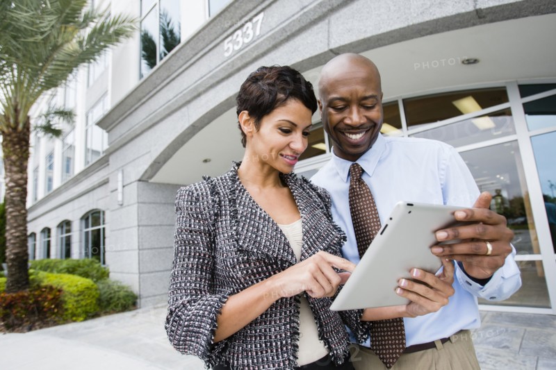 Business people using tablet computer outdoors
