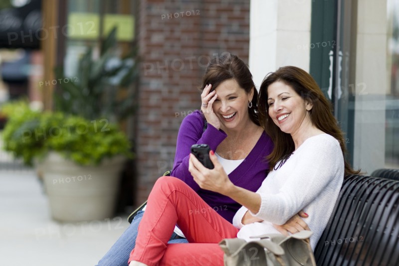 Caucasian women using cell phone on city bench