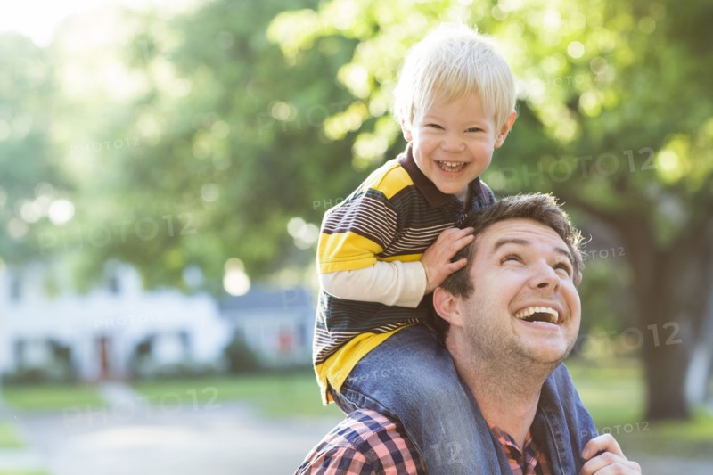 Caucasian father carrying son on shoulders