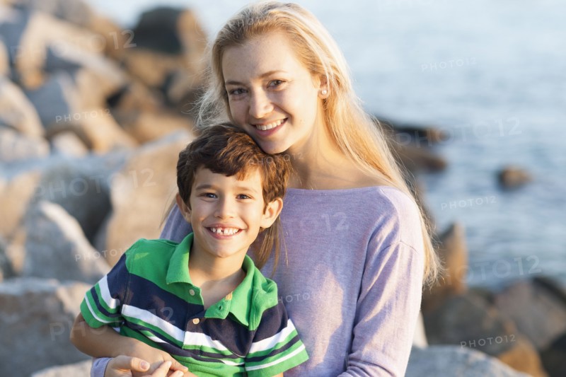 Caucasian brother and sister smiling on rocky beach