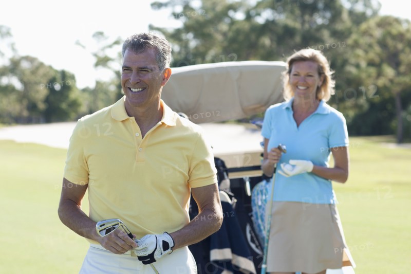 Caucasian couple playing golf on course