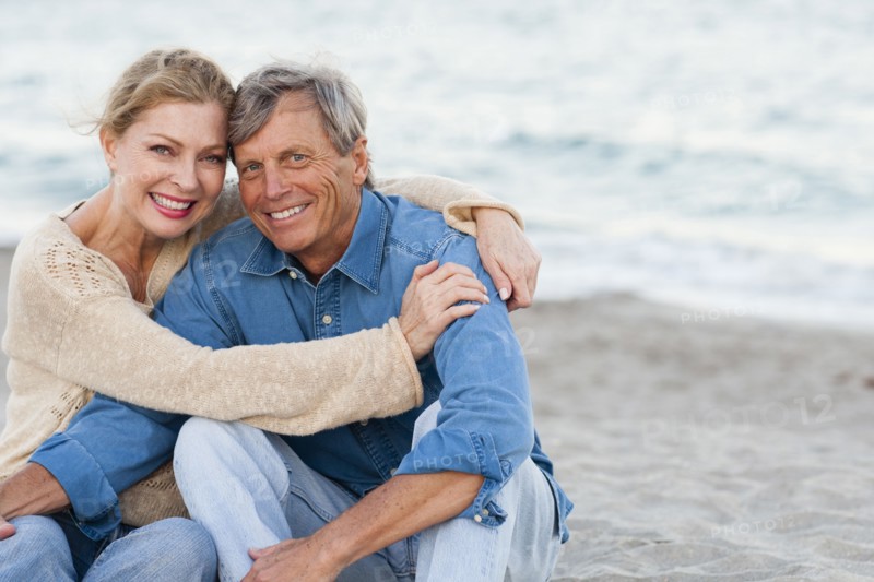 Older Caucasian couple hugging on beach