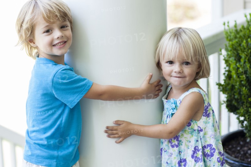 Caucasian children hugging column outdoors
