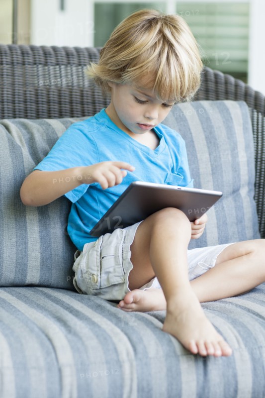Caucasian boy using digital tablet on sofa