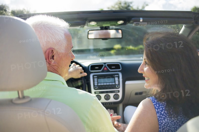 Older Caucasian couple driving in convertible