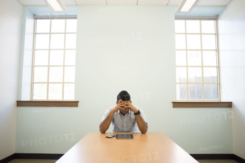 Frustrated Asian businessman using digital tablet in office