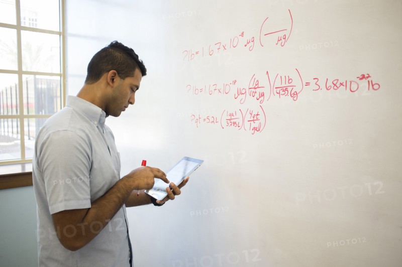 Asian businessman using digital tablet at whiteboard