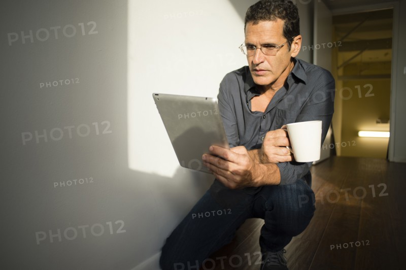 Hispanic businessman using digital tablet in office hallway