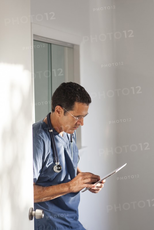 Hispanic doctor using digital tablet in hallway