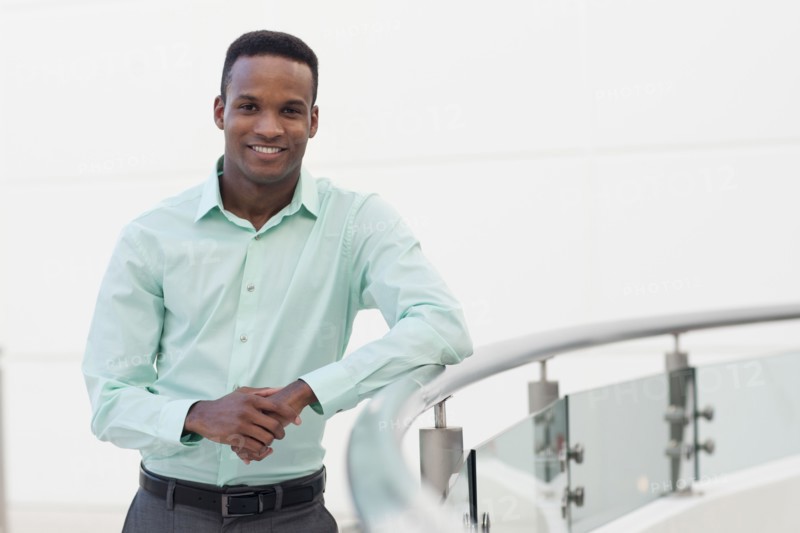 Black businessman leaning on railing