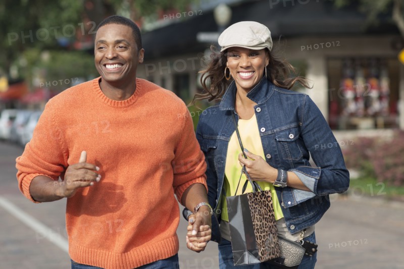 Couple holding hands and walking on sidewalk