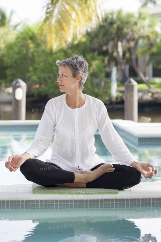 Woman meditating by still swimming pool