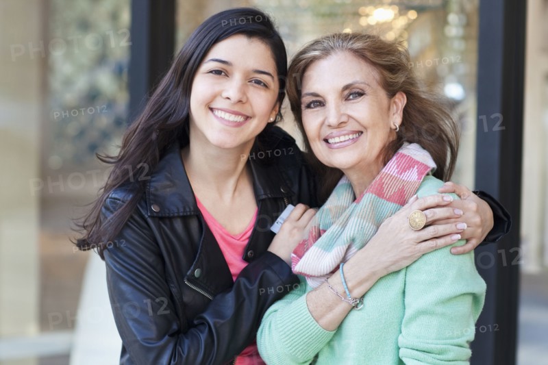 Mother and daughter hugging outside store