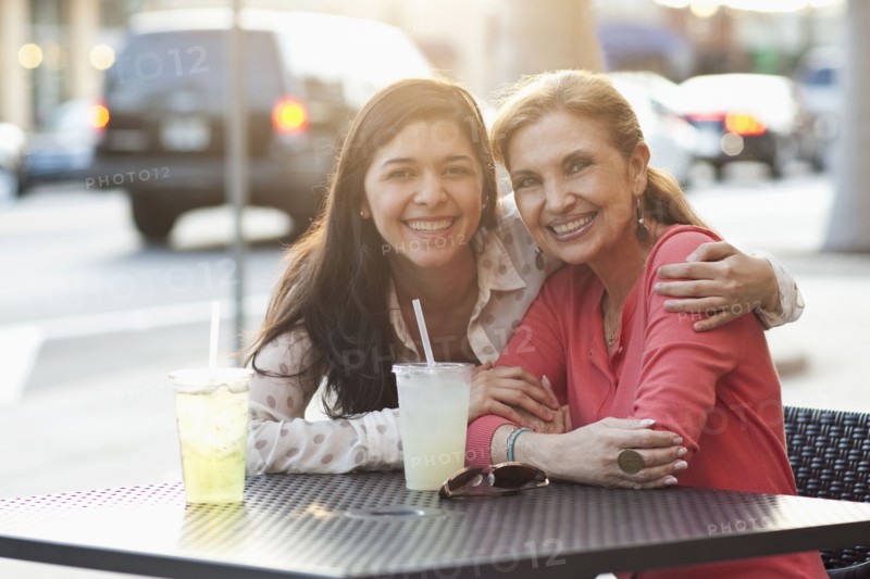 Mother and daughter hugging at sidewalk cafe