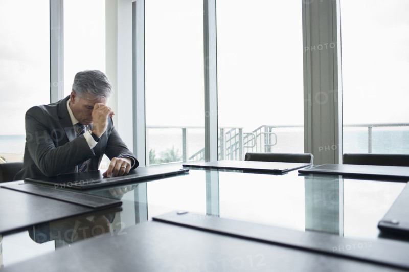 Caucasian businessman brooding at empty conference table