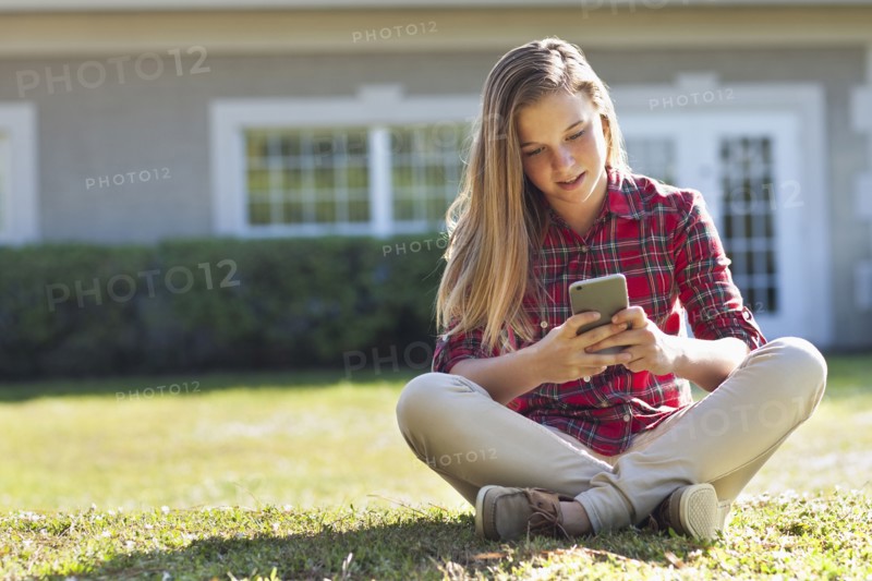 Caucasian girl using cell phone in backyard