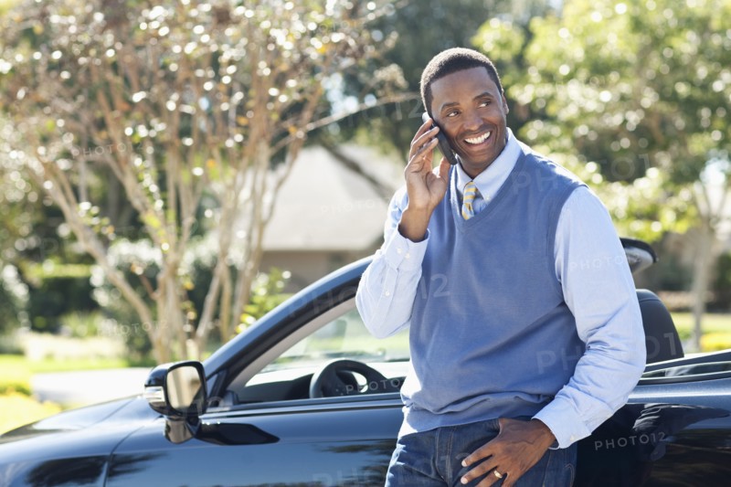 Black man talking on cell phone at convertible