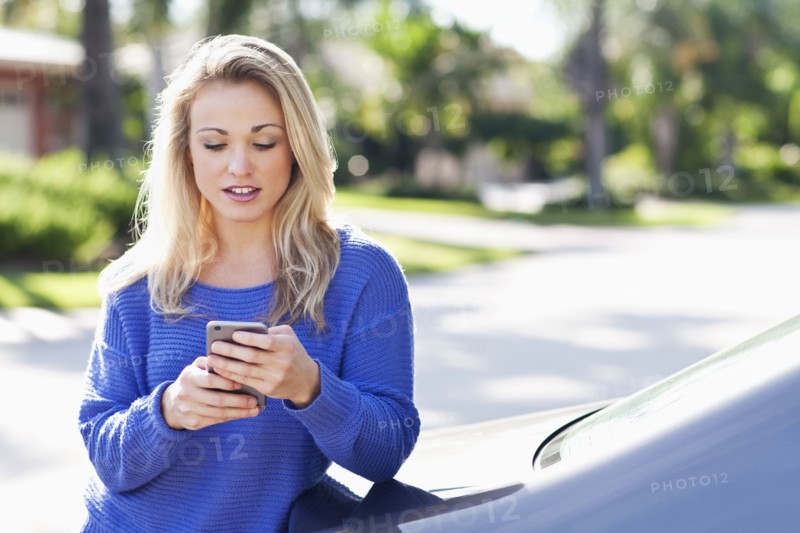 Caucasian woman using cell phone outside car