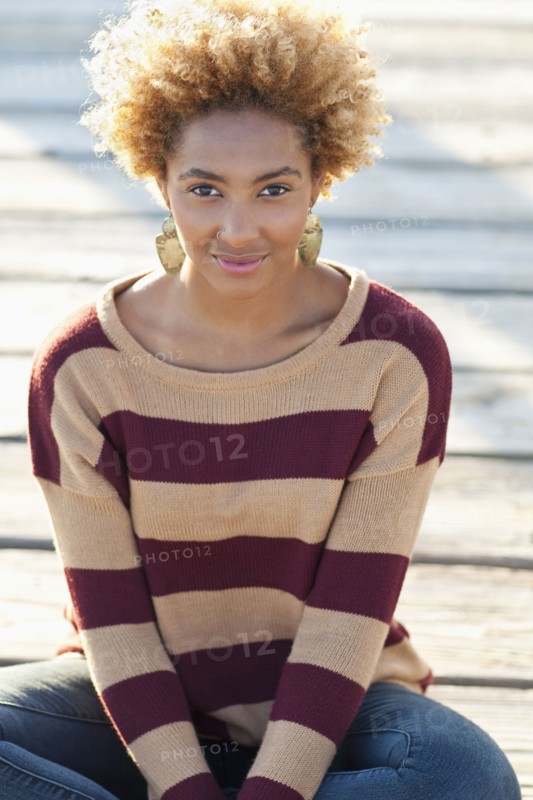 Black woman sitting on wooden boardwalk