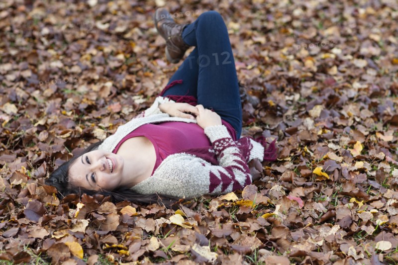 Hispanic teenage girl laying in autumn leaves