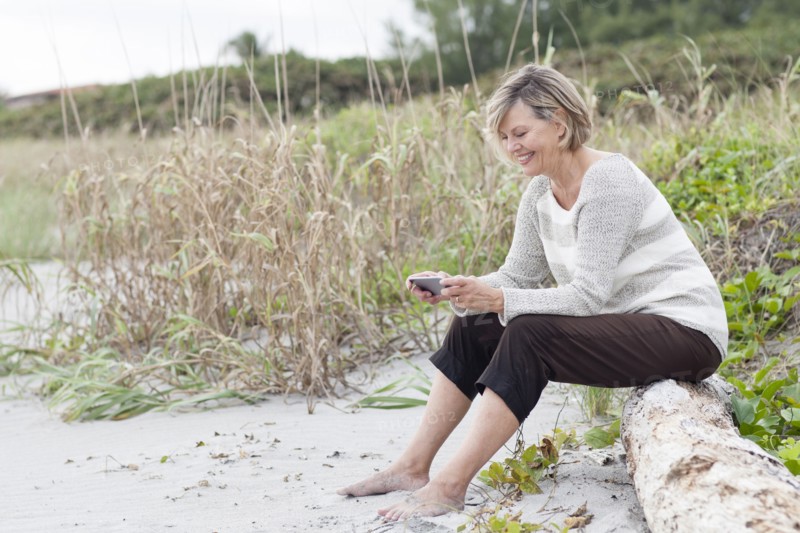 Caucasian woman using cell phone on beach