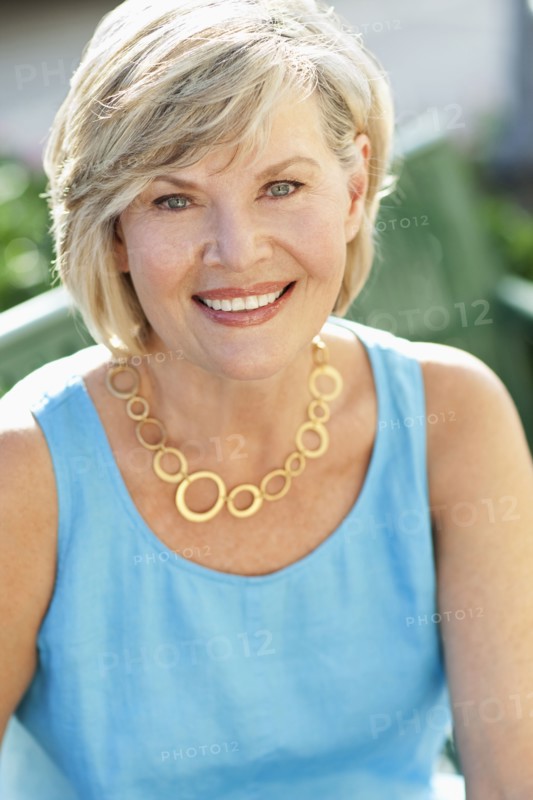 Smiling Caucasian woman sitting on park bench