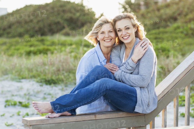 Caucasian mother and daughter hugging on beach