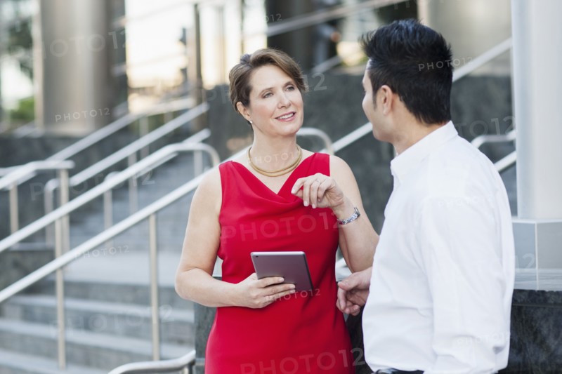 Business people using digital tablet near staircase