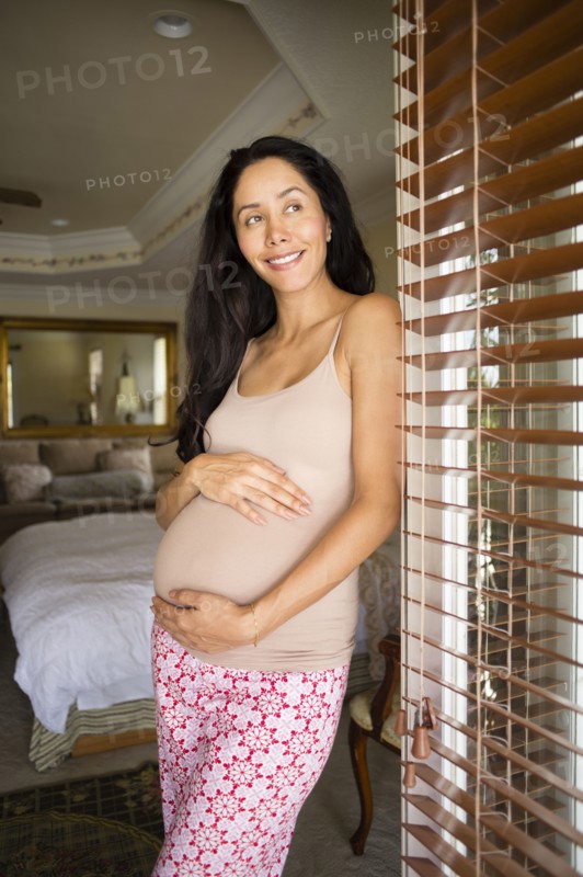 Pregnant Hispanic woman holding her belly