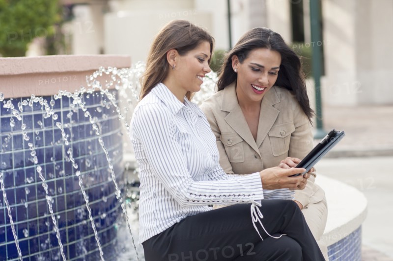 Businesswomen using digital tablet near fountain