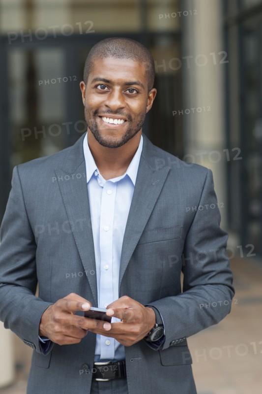 Black businessman using cell phone in city