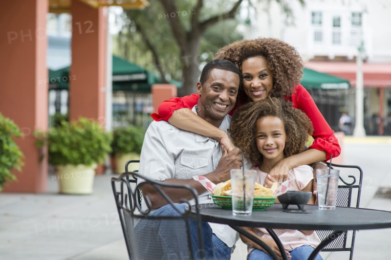 Family smiling at outdoor restaurant table