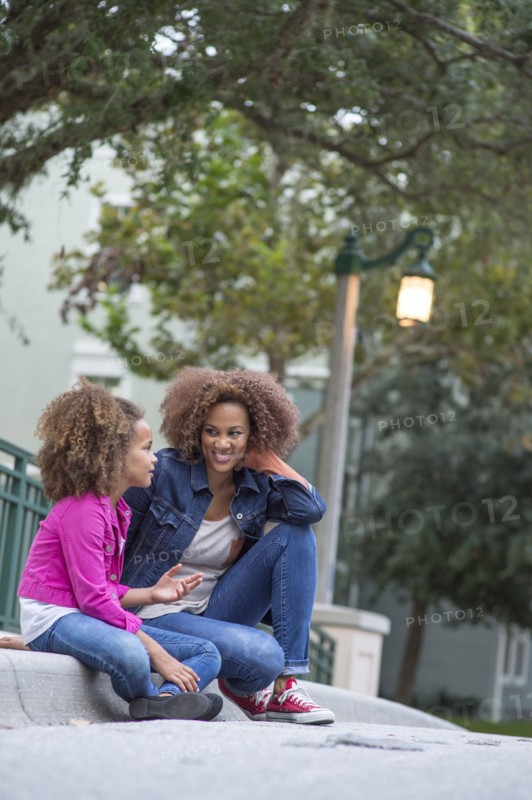 Mixed race mother and daughter sitting outdoors
