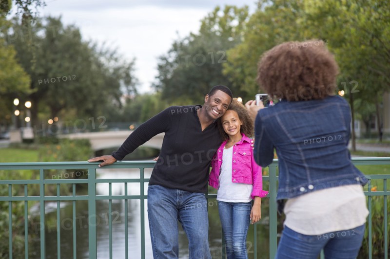 Mother photographing family on bridge