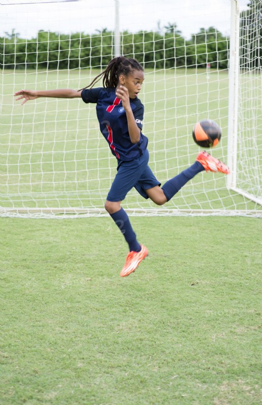 Mixed race boy kicking soccer ball on field