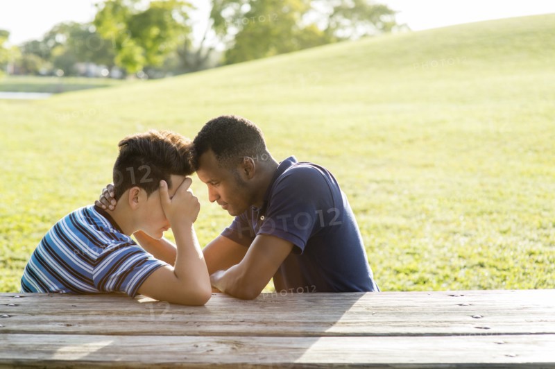 Father and son talking at table in park