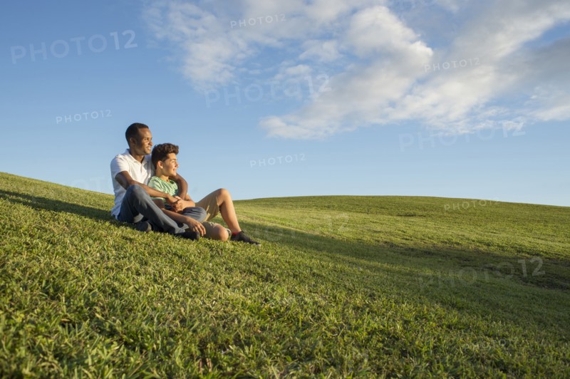 Father and son sitting in grass