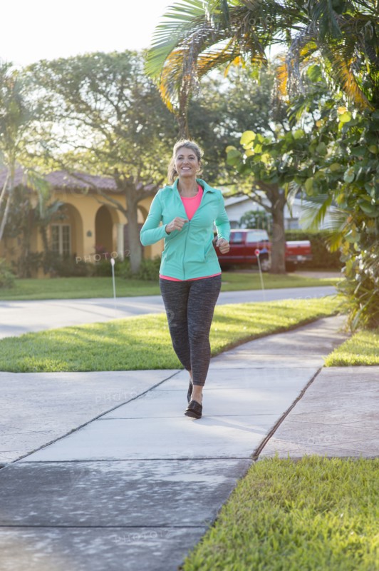 Caucasian woman jogging on sidewalk