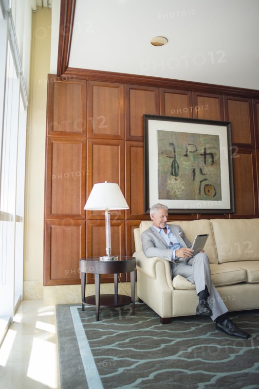 Caucasian man sitting on sofa using digital tablet