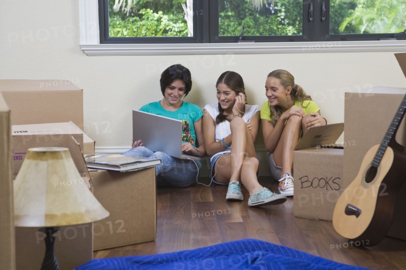 Hispanic teenage girls and woman using laptop