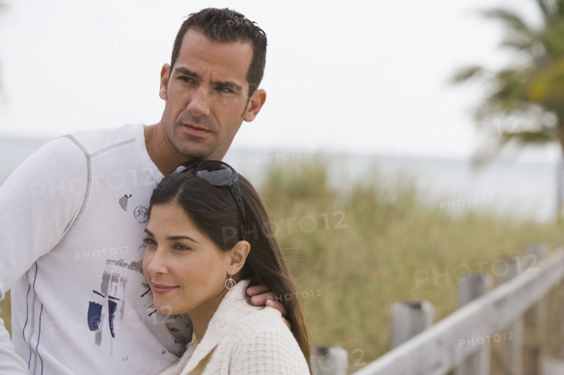 Hispanic couple hugging near ocean