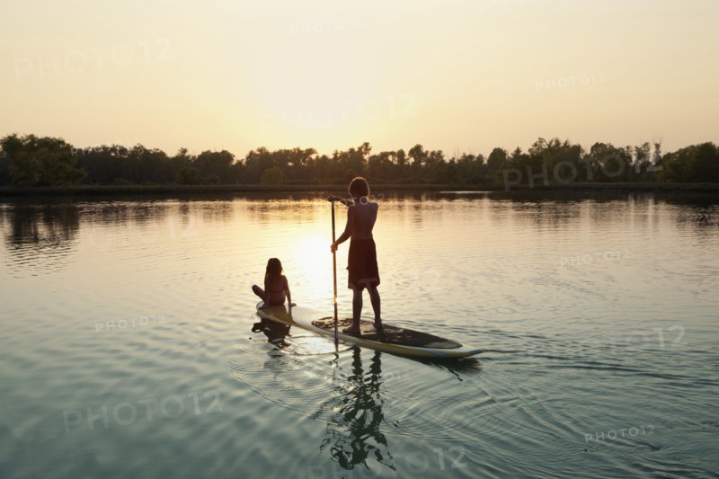 Caucasian boy and girl on paddleboard on lake