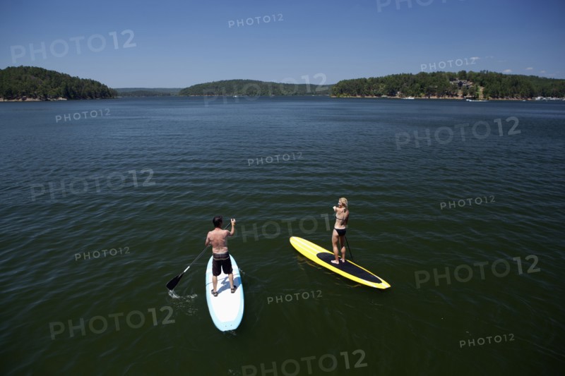 Caucasian couple on paddle boards on lake