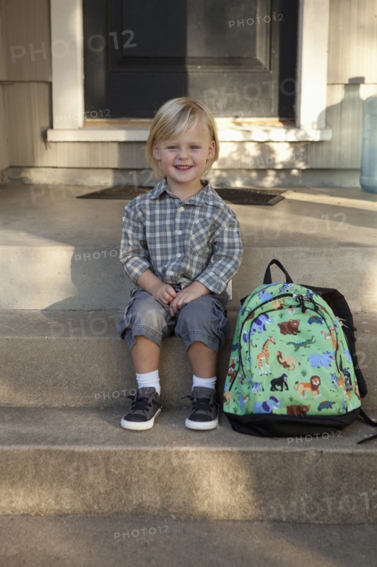 Caucasian boy with backpack on front steps