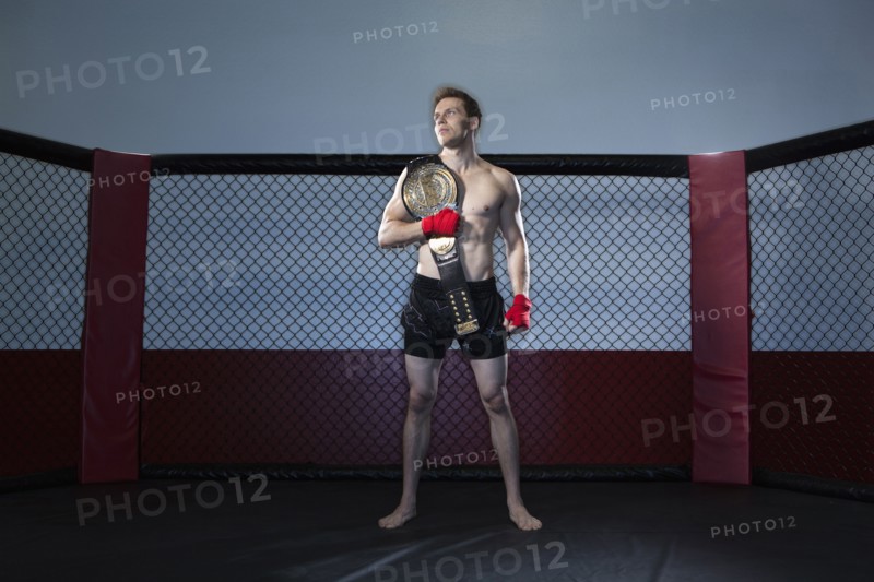 Caucasian cage fighter holding championship belt