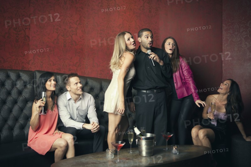 Friends singing karaoke together in nightclub