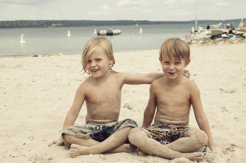 Caucasian brothers hugging on beach