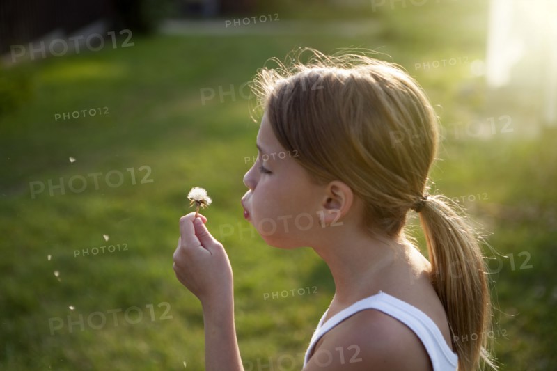 Caucasian girl blowing seeds off dandelion