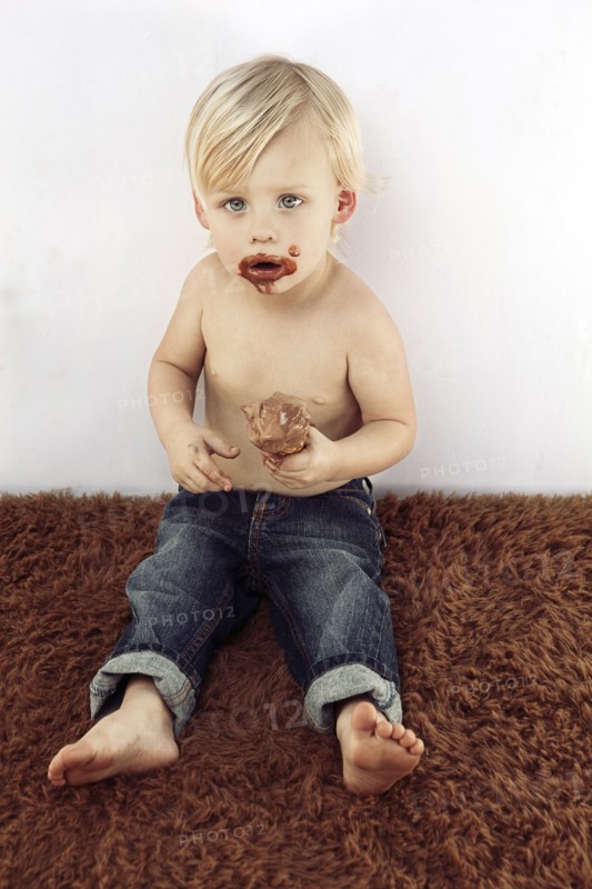 Messy Caucasian boy eating chocolate ice cream cone