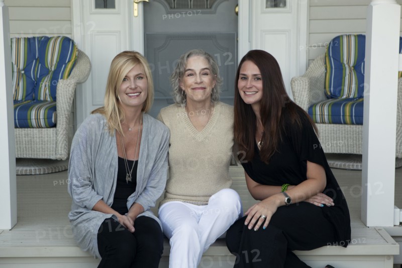 Caucasian mother and daughters smiling on front porch
